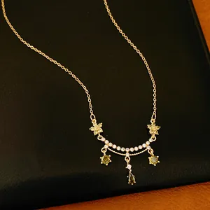 Close-up of 18k gold plated necklace featuring floral and teardrop zirconia charms.