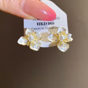 Close-up of elegant white flower stud earrings with pearl center and zircon