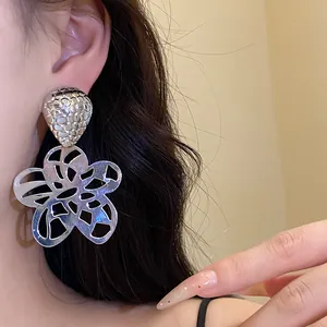 Detailansicht silberfarbener Metallohrringe mit hohlem Blumenanhänger und Vintage-Charme
