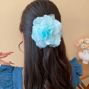Detailansicht einer eleganten hellblauen Mullblumen-Haarklammer auf dunklem Haar