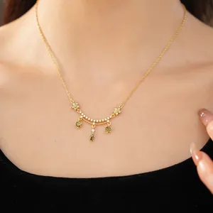 Close-up of 18k gold plated necklace with green zircon flowers and teardrop pendants.