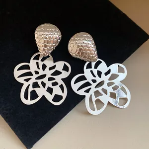Nahaufnahme von silbernen hohlen Blumen-Ohrring-Anhängern im Vintage-Stil für Damen