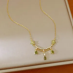 Close-up of 18k gold plated necklace with green zirconia flower and waterdrop pendant.