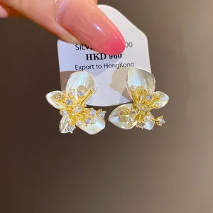 Detailed macro view of white pearl butterfly earrings with sparkling cubic zirconia.