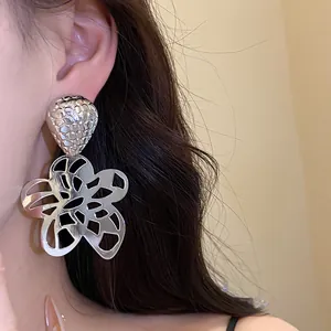 Detailaufnahme eines stilvollen silbernen hohlen Blumenohrrings am Ohr getragen