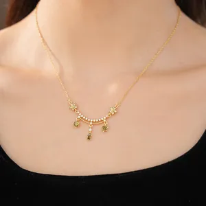 Close-up of elegant 18k gold plated necklace with flower and green teardrop zircon
