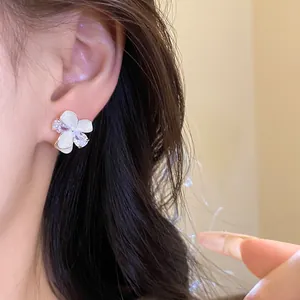 Detail of white flower stud earrings with sparkling zircons on model ear