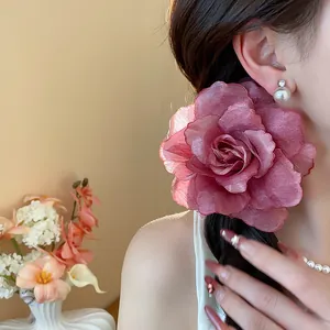 Detail einer eleganten großen staubrosafarbenen Gazeblumen Haarspange am Modell
