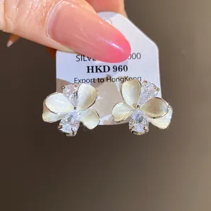 Close-up detail of white pearl petal flower stud earrings with shimmering cubic zirconia stones