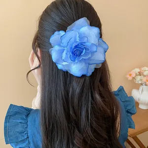 Große blaue Stoffblume Haarspange auf langem gewelltem Haar für einen eleganten Look