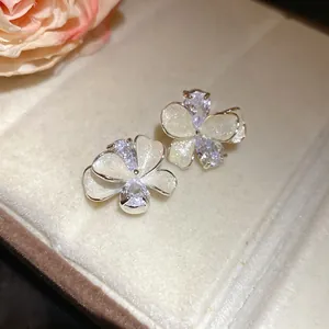 Close-up of elegant flower stud earrings with white petals and clear zircon crystals