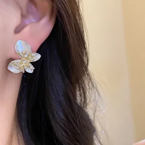 Close-up of butterfly stud earring with white pearlescent wings and zircon details