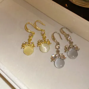 Detailed view of gold and silver hook earrings with round resin stones and crystals