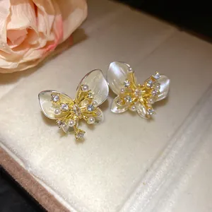 Detailed close-up of elegant butterfly stud earrings with white pearls and sparkling zircons