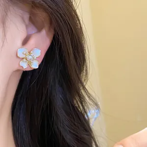Elegant flower stud earring with white pearl and sparkling zircon accents on model ear