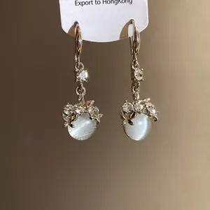 Detailed view of silver drop earrings with shimmering resin beads and rhinestone accents.