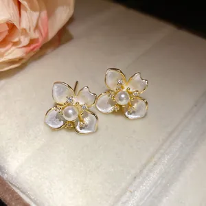 Close-up of elegant flower stud earrings featuring central white pearl and sparkling zircons