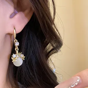 Detail shot of elegant gold drop earrings with rhinestone butterflies and resin pendant