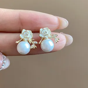 Primo piano di orecchini a lobo a fiore placcati oro 18k con zirconi e perle.