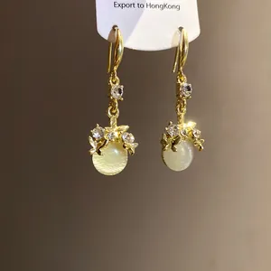 Elegant gold butterfly earrings detail with resin cat's eye beads and sparkling rhinestones