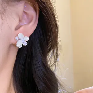 Macro detail shot of elegant white flower stud earrings with sparkling zircon on ear