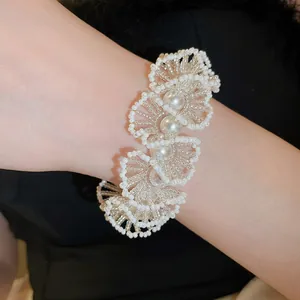 Close-up detail of a white beaded pearl bracelet with floral lace design