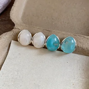 Dettaglio di orecchini a goccia in acrilico minimalisti in bianco crema e blu turchese