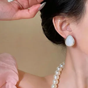 Primo piano dettagliato di eleganti orecchini a goccia in acrilico bianco su modella