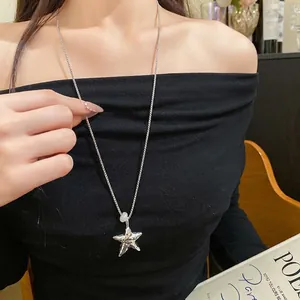Collana con ciondolo a stella plissettata indossata da una modella in top nero