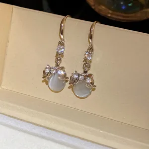 Close-up of elegant gold earrings with resin cat-eye stones and sparkling CZ stones