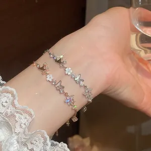 Close-up detail of elegant zircon butterfly and flower shell bracelet on a female wrist.