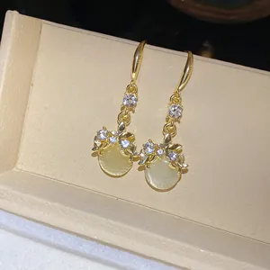 Close-up of elegant gold dangle earrings with crystals and round yellow resin pendants