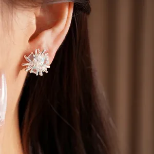 Boucles d'oreilles fleurs en argent avec zircons étincelants portées par un mannequin