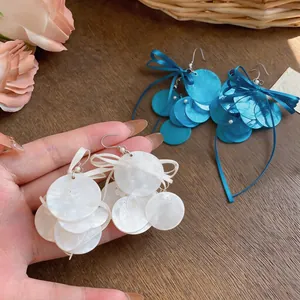 Λεπτομέρεια από λευκά σκουλαρίκια από κοχύλι με κομψό σχέδιο με σατέν φιόγκο