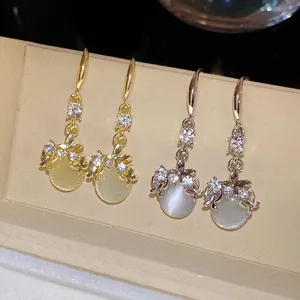 Detailed close-up of elegant gold and silver hook earrings with sparkling rhinestone accents.