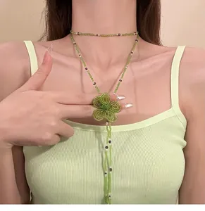 Vista dettagliata di un'elegante collana di perline di vetro verde con fiore e nappe
