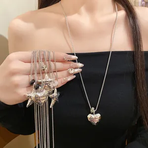 Modella indossa collana con ciondolo a cuore in metallo stropicciato e stelle.