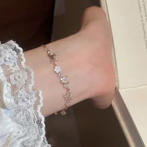 Close-up of rose gold butterfly and flower bracelet with zircon and mother-of-pearl detail.
