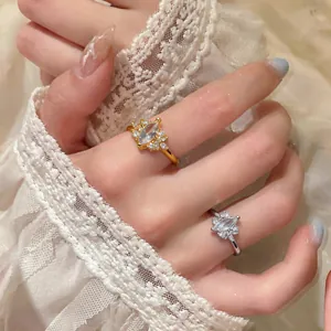 Close-up of elegant marquise zircon rings in gold and silver on a delicate lace background.