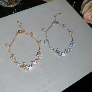 Detailed view of elegant butterfly and flower bracelets with shimmering zircons and pearl.