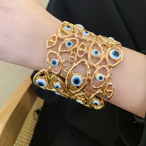 Dettaglio di un bracciale rigido dorato traforato con decorazioni a occhio turco