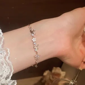 Exquisite detail of a zircon butterfly and flower bracelet worn on a wrist.