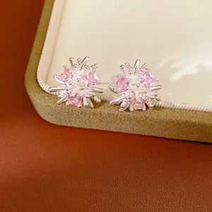 Vue macro d'élégantes boucles d'oreilles fleur en argent avec zircons roses sur boîte