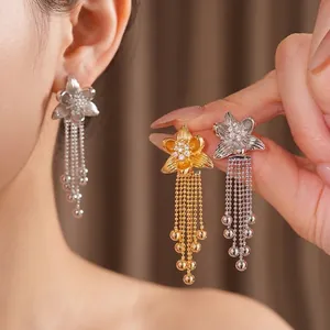 18k gold plated zircon flower tassel earrings shown on model and held in hand.