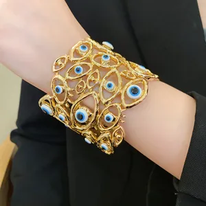 Vista dettagliata di un bracciale vintage dorato con motivi a occhio blu sul polso