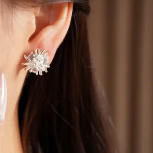 Détail en gros plan de boucles d'oreilles fleurs en argent avec zircons bleus brillants