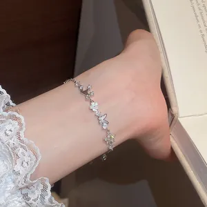 Close-up of zircon butterfly and flower bracelet with shell accents on wrist