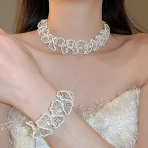 Detail showing an elegant white beaded lace-style pearl necklace and bracelet set on a model