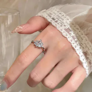 Detail of a dainty silver ring with sparkling oval zircon worn on a feminine hand.