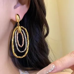 Vista detallada de elegantes pendientes ovalados retorcidos tricolores en la oreja
